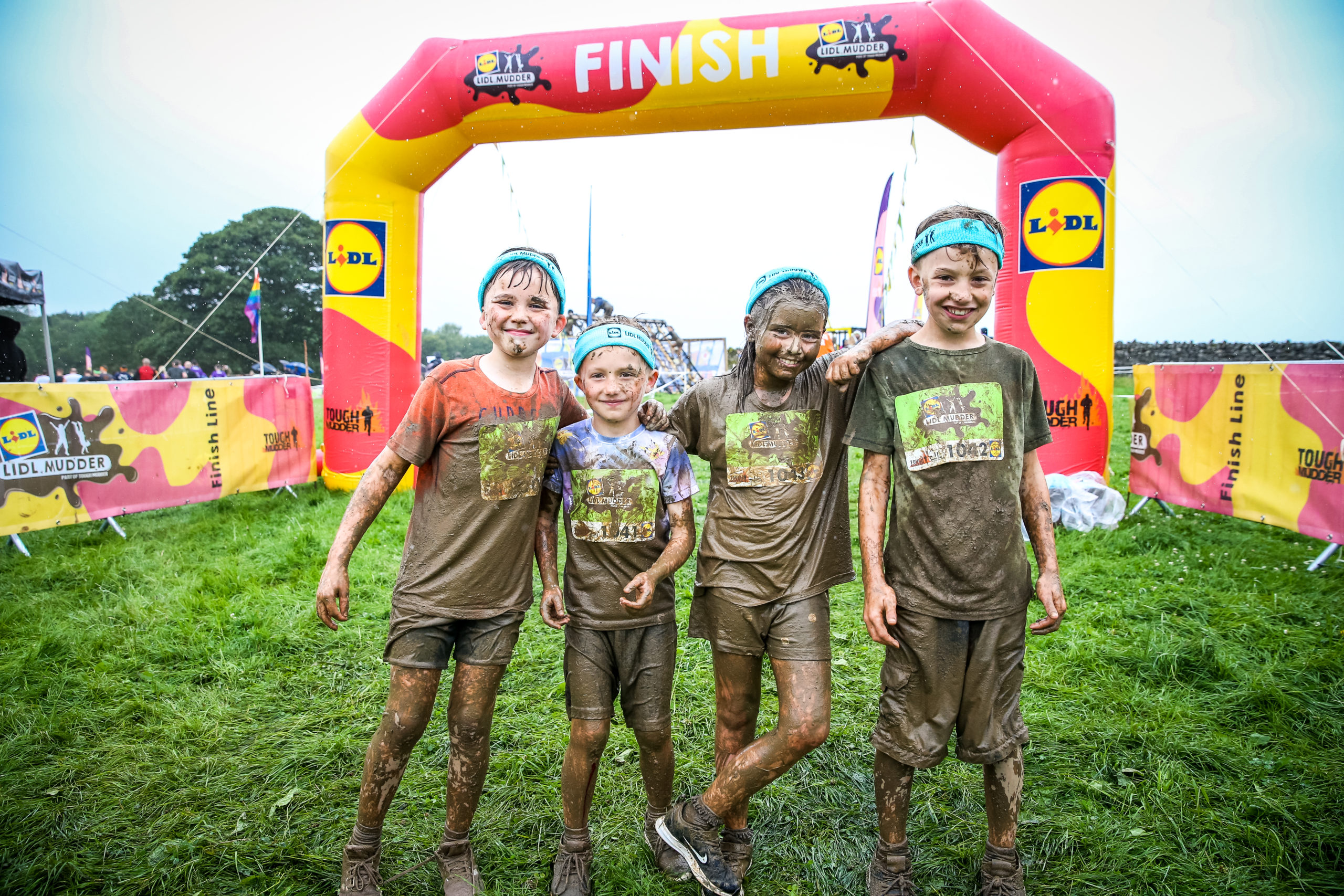 Four muddy children wearing blue headbands